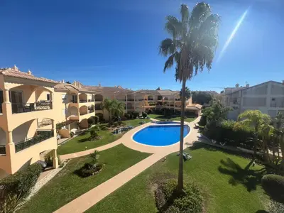 an apartment complex with a swimming pool and a palm tree at Praia Village by Garvetur in Quarteira