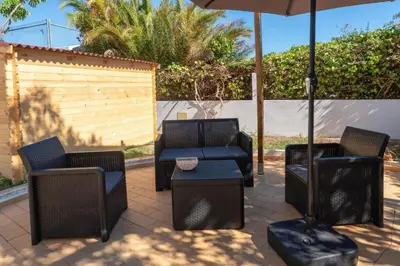 a patio with three chairs and an umbrella at Blife Sunya private rooms near airport and nature in Faro