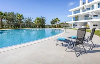 a swimming pool with two chairs next to a building at Miami green in Vilamoura