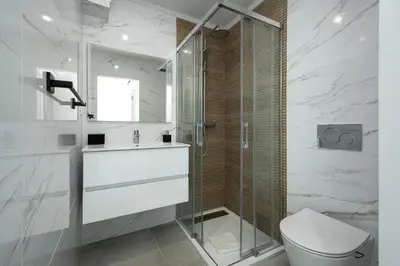 a bathroom with a toilet and a glass shower at Casa Pereira - Guest House Faro City Center in Faro