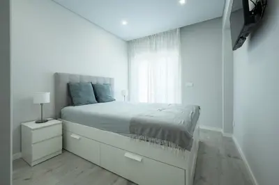 a white bedroom with a large bed and a window at Casa Pereira - Guest House Faro City Center in Faro