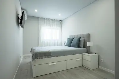 a white bedroom with a bed and a window at Casa Pereira - Guest House Faro City Center in Faro