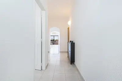 a hallway with white walls and a black refrigerator at Le Bleu de la Mer in Albufeira