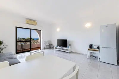 a living room with a white table and a refrigerator at Le Bleu de la Mer in Albufeira