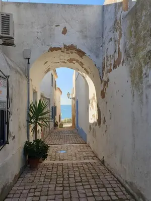 an alley with an archway in a town with the ocean at Casa da Porta da Praia - 1 Bedroom Castle Wall Loft in Albufeira