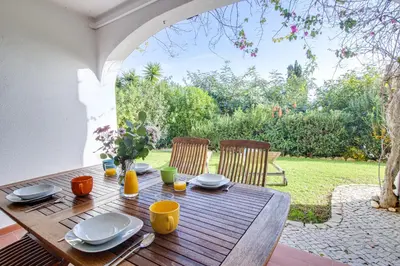 a wooden table with plates and utensils on it at Relaxing 2BD Apt 500m Beach w AC WiFi Pool in Albufeira