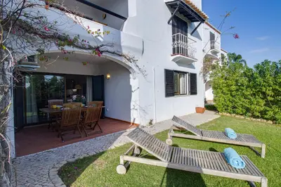 a patio with two wooden benches in front of a house at Relaxing 2BD Apt 500m Beach w AC WiFi Pool in Albufeira