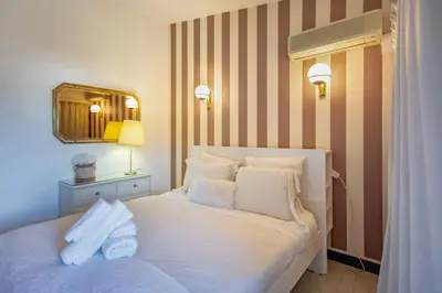 a bedroom with a white bed with a striped wall at Villa Lina - Vilamoura in Quarteira
