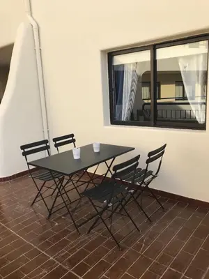 a table and chairs with a window in a room at Beautiful T2 Apartamento Olhos do Mar in Olhos de Água