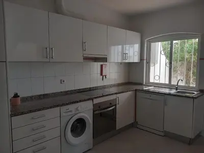 a kitchen with white cabinets and a washing machine at Vilamoura Pinhal Golf Course in Quarteira