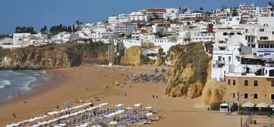 a beach with umbrellas and a crowd of people at Casa da Porta da Praia - 3 Bedroom Castle Wall House in Albufeira