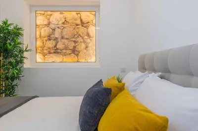 a bedroom with a bed with yellow pillows and a window at Casa da Porta da Praia - 3 Bedroom Castle Wall House in Albufeira