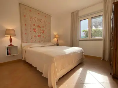 a bedroom with a white bed and a window at Casa Manacá Vilamoura in Quarteira
