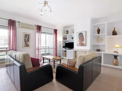 a kitchen with white cabinets and a dining room with a table at Apartment Kaya- Sunny Way by Interhome in Albufeira