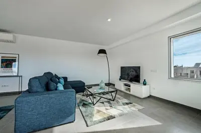 a living room with a blue couch and a tv at Lovely Modern Apartment With Pool in Albufeira
