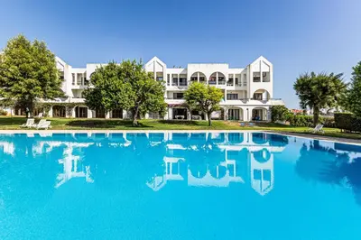 a large pool in front of a large white building at Ground floor with direct access to swimming pool in Albufeira