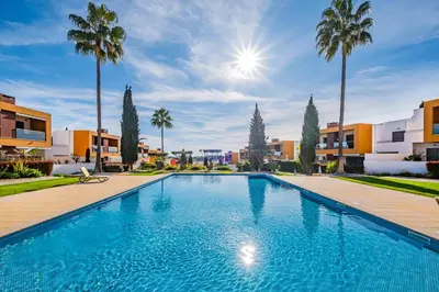 a swimming pool with palm trees and buildings at Vitismar Praia Algarve in Guia