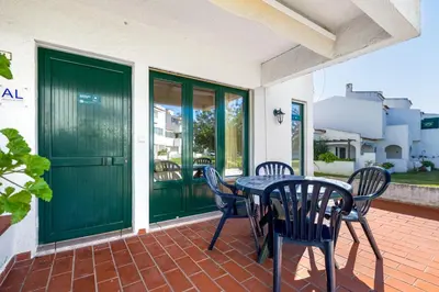 a table and chairs on a patio with green doors at Bright 3BDR Vilamoura Retreat Flat by LovelyStay in Quarteira
