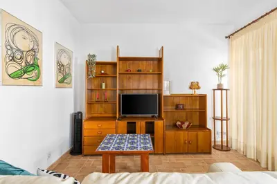 a living room with a tv on a wooden entertainment center at Bright 3BDR Vilamoura Retreat Flat by LovelyStay in Quarteira