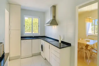 a kitchen with a washer and dryer and a table at Villa Mar by Sunny Deluxe in Albufeira