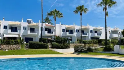 a villa with palm trees and a swimming pool at Jardim da Oura by Check-in, Portugal in Albufeira