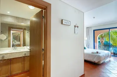 a bedroom with a bed and a bathroom with a sink at F5 Vila Sol G Pool & Golf in Vilamoura in Quarteira