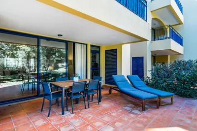 a patio with a wooden table and blue chairs at F5 Vila Sol AI Pool & Golf in Vilamoura in Quarteira