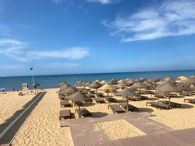 a beach with chairs and umbrellas and the ocean at Solar Vilamoura Relaxing Apartment Stay in Quarteira