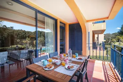 a wooden table on a balcony with food on it at F5 Vila Sol Q Pool & Golf in Vilamoura in Quarteira
