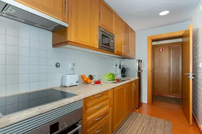a kitchen with wooden cabinets and a counter top at F5 Vila Sol AP Pool & Golf in Vilamoura in Quarteira