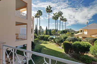 a balcony of a house with palm trees and a yard at Las Palmeiras Vilamoura in Quarteira
