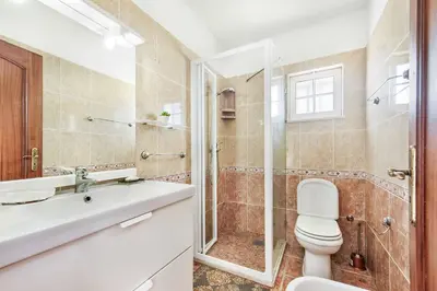 a bathroom with a toilet and a shower and a sink at Villa Portela in Loulé