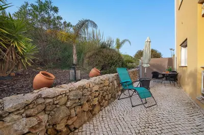 a stone retaining wall with two chairs and a table at Flat With Pool, Old Town Albufeira in Albufeira