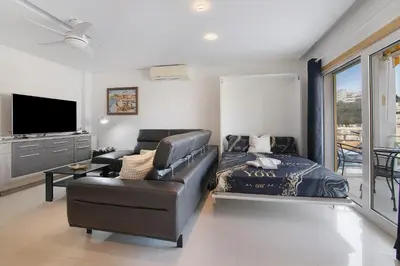 a living room with a leather couch and a bed at Flat With Pool, Old Town Albufeira in Albufeira