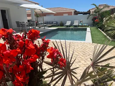 a pool with red flowers in front of a house at Casa Alegria in Tunes