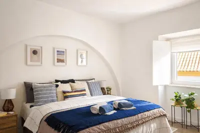 a bedroom with a bed with blue blankets and pillows at Varanda da Baixa, cosy apartment, top location, private terrace, barbecue, AC and Wi-Fi in Faro