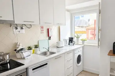 a white kitchen with a sink and a washing machine at Varanda da Baixa, cosy apartment, top location, private terrace, barbecue, AC and Wi-Fi in Faro