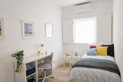 a white bedroom with a bed and a desk at Varanda da Baixa, cosy apartment, top location, private terrace, barbecue, AC and Wi-Fi in Faro