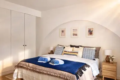 a bedroom with a bed with a blue blanket at Varanda da Baixa, cosy apartment, top location, private terrace, barbecue, AC and Wi-Fi in Faro