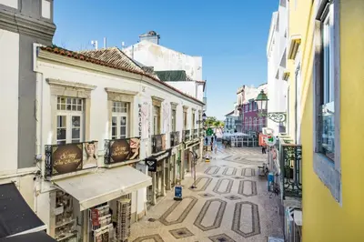 a woman walking down a street with an umbrella at Faro Downtown in Faro