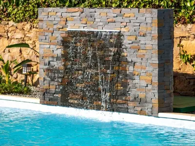 a waterfall in a stone wall next to a swimming pool at Holiday Home Lotus Villa 2- Albufeira by Interhome in Albufeira