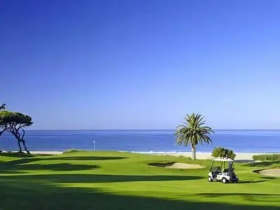 a golf cart on a green with the ocean in the background at Apartment mit Balkon by Interhome in Albufeira
