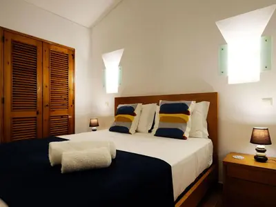 a bedroom with a large bed with blue and yellow pillows at Holiday Home Lotus Villa- Albufeira by Interhome in Albufeira