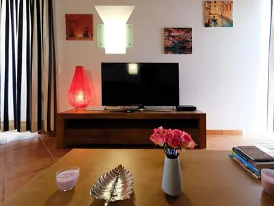 a living room with a television and a table with flowers at Holiday Home Lotus Villa- Albufeira by Interhome in Albufeira