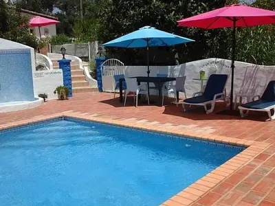 a pool with two umbrellas and a table and chairs and a table at Holiday Home Berghütte Villa Romao by Interhome in Barranco de Apra