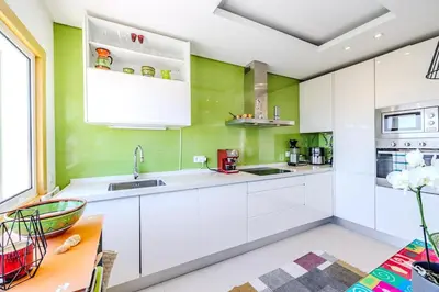 a kitchen with white cabinets and green walls at Garden Hill Haven - Old Town Albufeira - Sea View in Albufeira