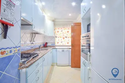 a large kitchen with white appliances and blue cabinets at Vitoria 1 by MTPhomes in Albufeira