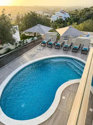 a large swimming pool with chairs and umbrellas at Villa Nova En-suite luxury, private pool, sea view in Albufeira