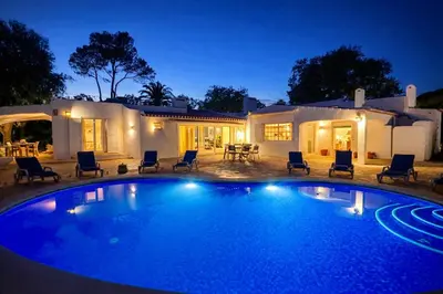 a pool with chairs and a palm tree at night at Villa Morocco with Heated Private Pool for 12 Guests in Albufeira in Albufeira