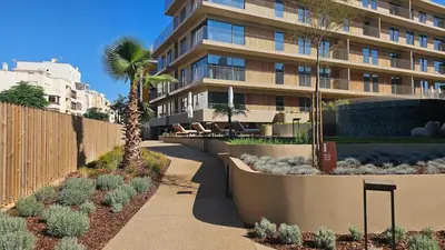 a building with a palm tree next to a sidewalk at Sweet Horizon in Quarteira